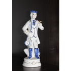 Декоративная, фарфоровая статуэтка, мальчика в костюме викторианской эпохи, держащего музыкальный инструмент.