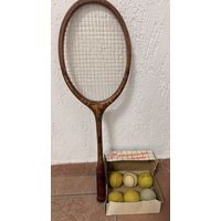 Винтажный набор, состоящий из деревянной теннисной ракетки и коробки с теннисными мячами.