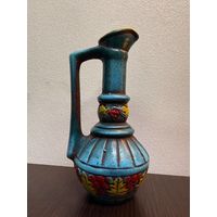 Винтажный керамический кувшин, украшенный рельефным узором из виноградных гроздьев и листьев.